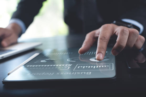 istock Businessman working on digital tablet and laptop at modern office, analyzing business document with financial graph, market report on digital tablet, business data analysis concept 1453618956