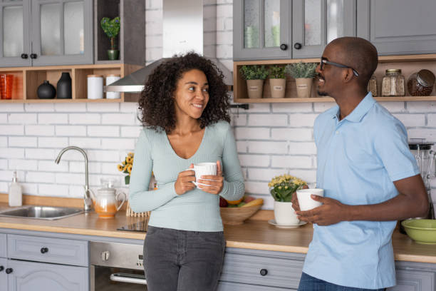 istock Affectionate black spouses, holding cups, drinking coffee and spending time in kitchen together, young loving african american man and woman having hot drinks and enjoying domestic weekend, free space 1453621012