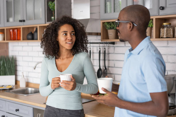 istock Affectionate black spouses, holding cups, drinking coffee and spending time in kitchen together, young loving african american man and woman having hot drinks and enjoying domestic weekend, free space 1453621015