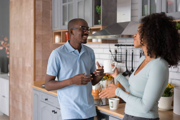 istock Affectionate black spouses, holding cups, drinking coffee and spending time in kitchen together, young loving african american man and woman having hot drinks and enjoying domestic weekend, free space 1453621021