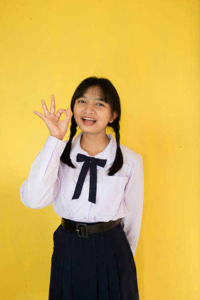istock Student girl in uniform on yellow background. 1453621084