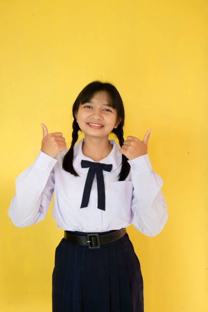 istock Student girl in uniform on yellow background. 1453621124