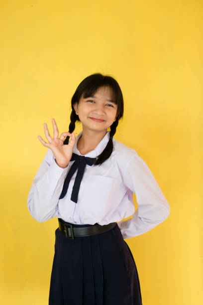 istock Student girl in uniform on yellow background. 1453621220