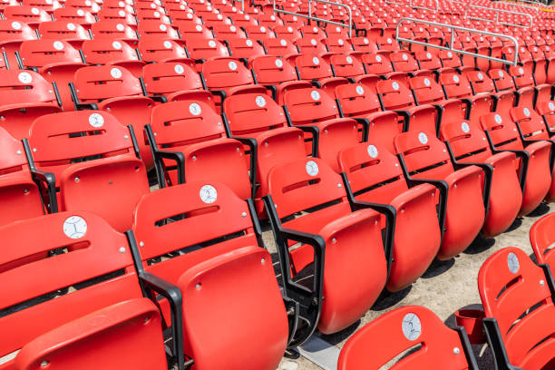Rows of empty, red bleacher seats with seat numbers inside baseball's. Rows of empty red bleacher seats in a stadium with numbers inside of baseball looking stickers. baseball stadium chairs stock pictures, royalty-free photos & images