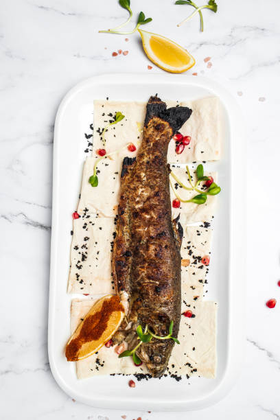 Baked trout fish with salt, lemon. Grilled trout. Fish dish fried fish fillet with vegetables. Ketogenic, keto or paleo diet lunch, Healthy food trend. vertical image. top view. place for text. pescado de trucha al horno con sal, limón. trucha a la plancha. plato de pescado filete de pescado frito con verduras. almuerzo de dieta cetogénica, ceto o paleo, tendencia de comida saludable. imagen vertical. vista superior. lugar para el texto