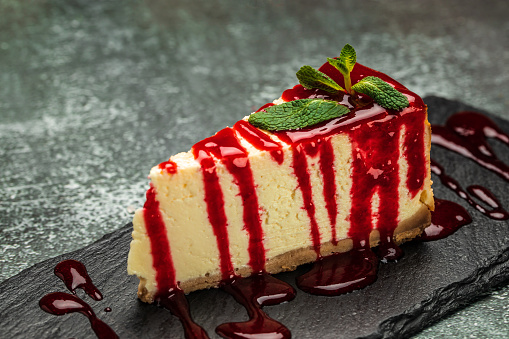 Piece of cheesecake with fresh strawberries jam and mint. Tasty homemade cheesecake.