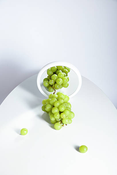 istock Vertical shot of white grape reflecting on the round mirror on a white background 1453628551