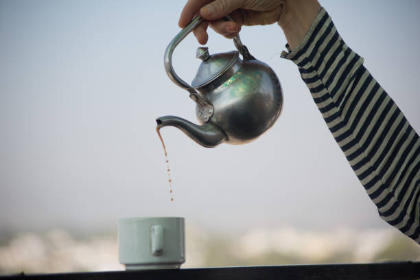 istock Close-up of hand pouring tea into a cup 1453629843