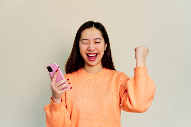 istock Cheerful Asian woman with smartphone on white background 1453633153