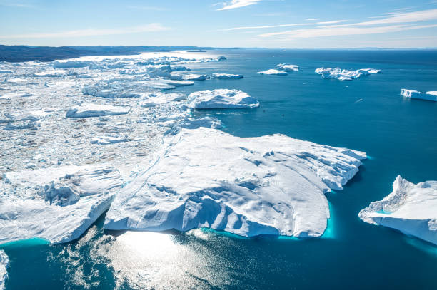 Aerial view of big icebergs in Greenland Huge icebergs are floating in the Kangerlua Icefjord, Ilulissat, Disko Bay, Greenland.the beautiful reflections of the ice into the arctic waters produces a light blu tonality which contrasts with the dark blu of the ocean's waters. The picture has been taken from a plane in the Unesco world heritage site ilulissat icefjord stock pictures, royalty-free photos & images