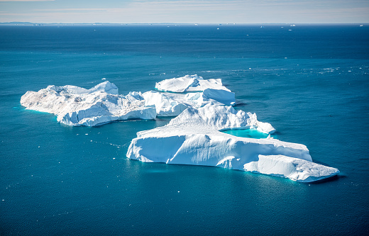 Huge icebergs floating in the Arctic ocean, in Ilulissat, Greenland, Unesco World Heritage, the arctic water is dark, and the icebergs stand out into the ocean, the picture has been taken from a plane