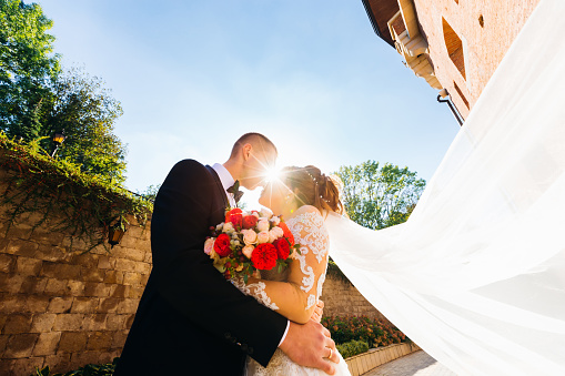 Light of sun rays between newlyweds. newlyweds embrace and want to kiss. bride holding wedding bouquet