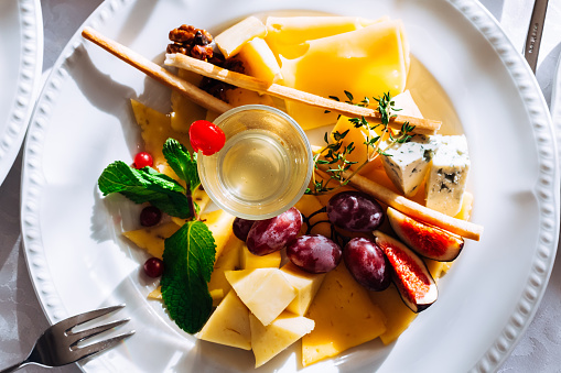Assortment of cheeses, honey and grapes on a white plate. wedding.