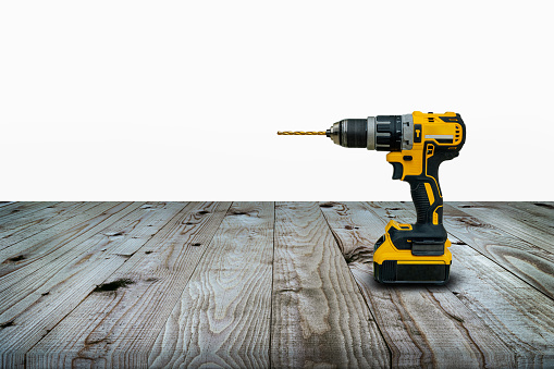 Power drill or Cordless screwdriver with battery for professional work in wooden background.