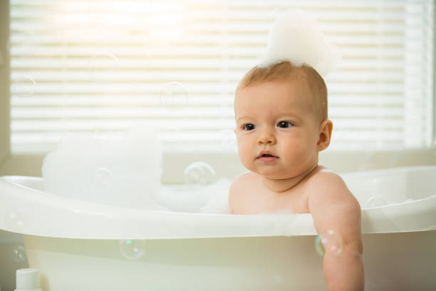 istock Cute little baby sitting in white bathtub 1453635227