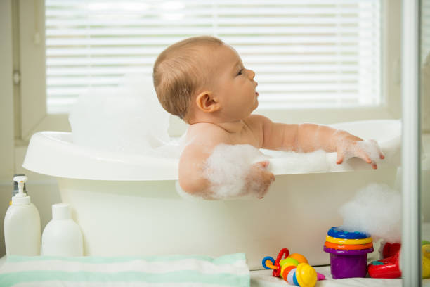 istock Cute little baby sitting in white bathtub 1453635281