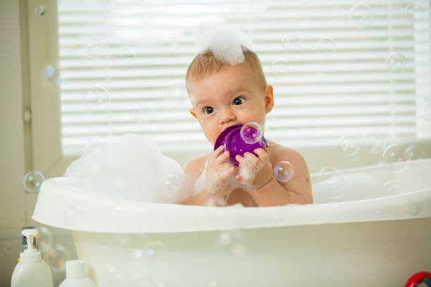 istock Cute little baby sitting in white bathtub 1453635351