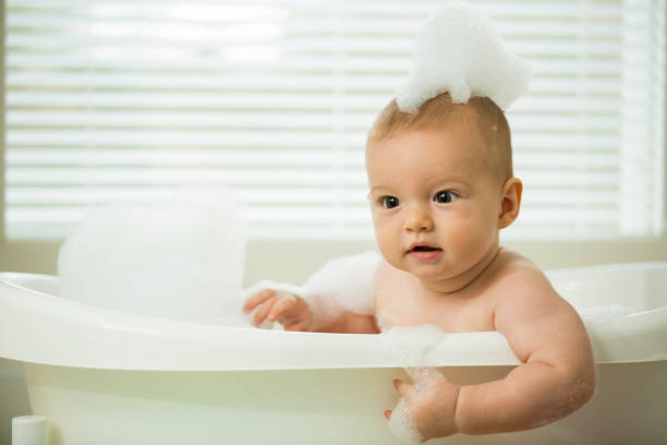 istock Cute little baby sitting in white bathtub 1453635352