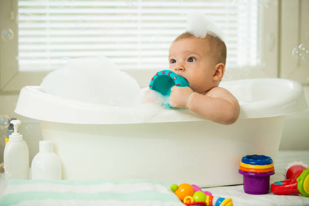 istock Cute little baby sitting in white bathtub 1453635526
