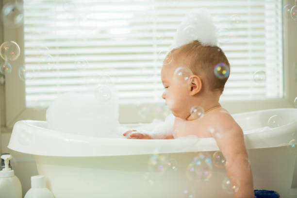 istock Cute little baby sitting in white bathtub 1453635527