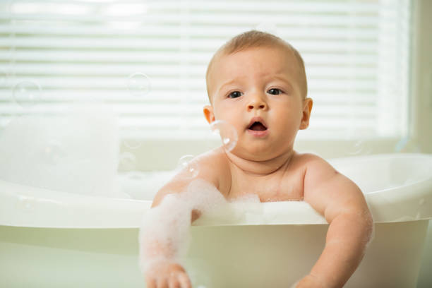 istock Cute little baby sitting in white bathtub 1453636264