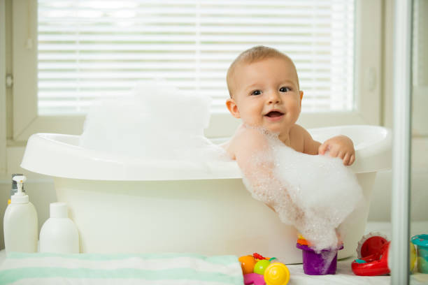 Cute little baby sitting in white bathtub stock photo