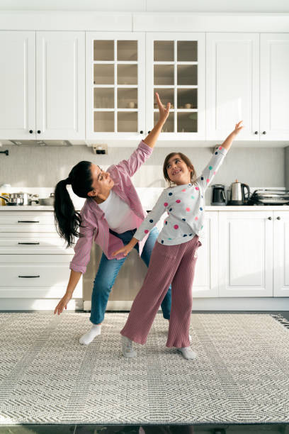 istock Happy young mom and little daughter dance at home 1453637241