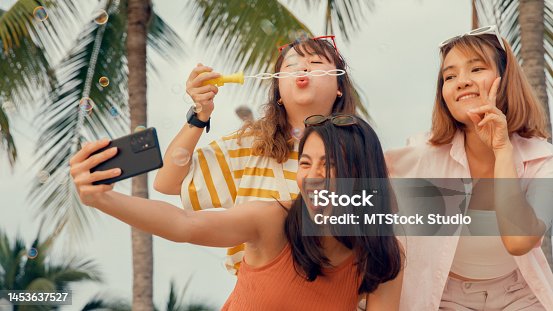 istock Group of young Asian woman using smartphone taking a selfie on tropical beach. 1453637527