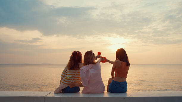 группа молодых азиатских женщин празднует и пьет алкоголь на тропическом пляже. - party beach indian ethnicity adult стоковые фото и изображения