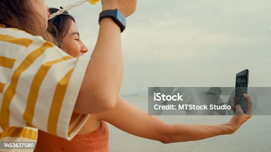 istock Close up of group young Asian woman using smartphone taking a selfie on tropical beach. 1453637580