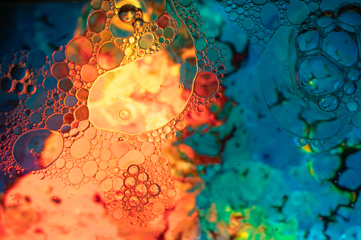 Abstract shapes and textures formed of bubbles and drops on a colored liquid background