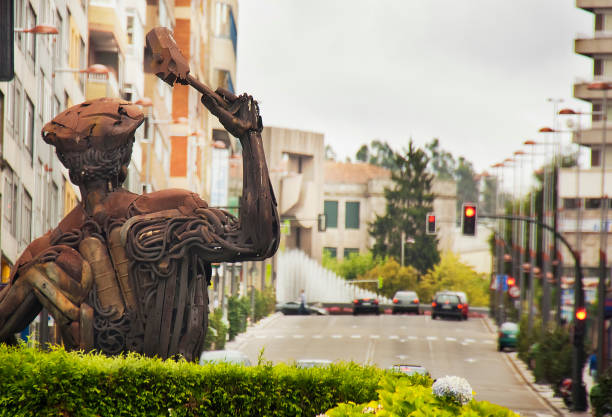 Townscape in Vigo, Coruña street and rear view of monument in industry town square. Vigo, Galicia, Spain. Vigo, Spain- August 7,2011: Townscape in Vigo, Coruña street and rear view of monument in industry town square. Iron pieces that give life to the figure of the metal worker from Vigo, effort Downtown district in Vigo, Galicia, Spain. vigo stock pictures, royalty-free photos & images