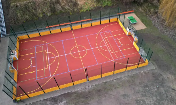 multifunctional outdoor playground for ball games at school. green artificial turf from a plastic carpet with lines. basketball hoops and soccer goals. around the grabbing high net and guardrails , multifunctional, guardrails, function, barriers