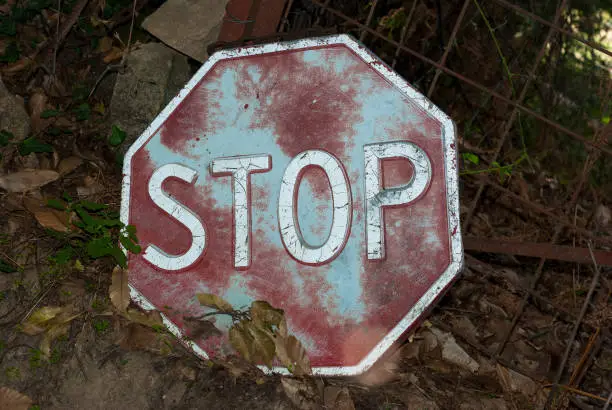 Photo of Old rusty Stop sign lying forgotten on the ground in the countryside