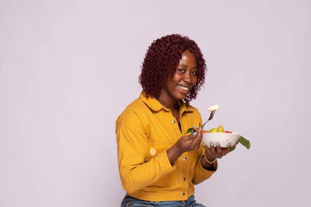 istock an african lady eating fruit salad 1453649505