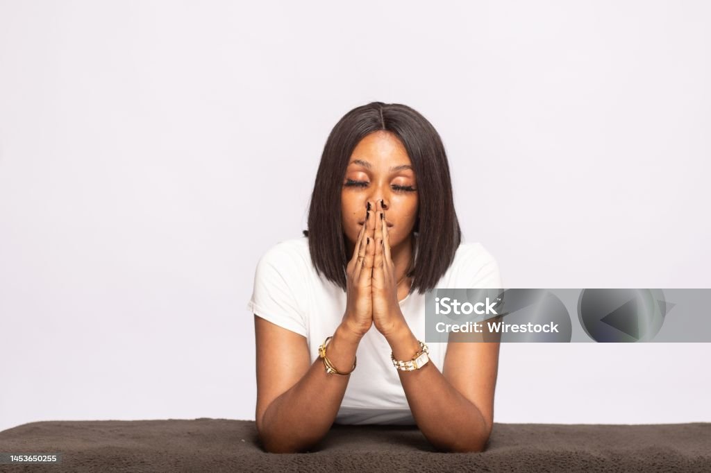 african lady saying her prayers young african lady saying her prayers Praying Stock Photo