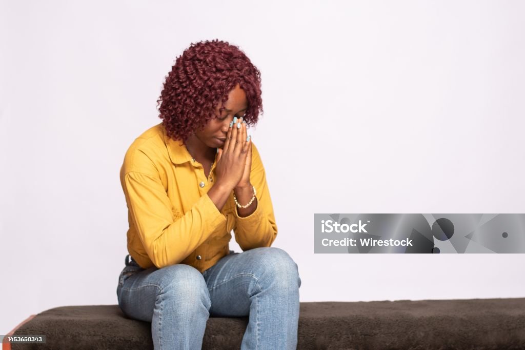 african lady saying her prayers young african lady saying her prayers Adult Stock Photo