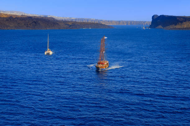 Discovering the Greek islands: horizon sea with tour boat and the typical caldera of Santorini.