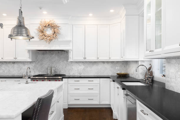 A white kitchen detail with a marble backsplash and large island.