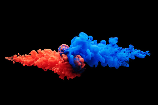 Collision of flow of red and blue ink on a black background. Abstract concept photo.