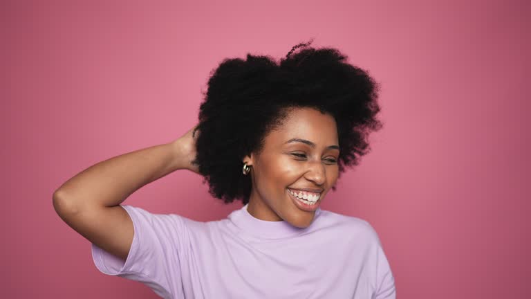 Young woman dancing on a pink background