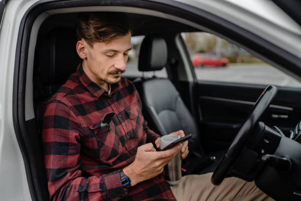 istock man hold cup with coffee use mobile phone sit in the car take a brake 1453659833