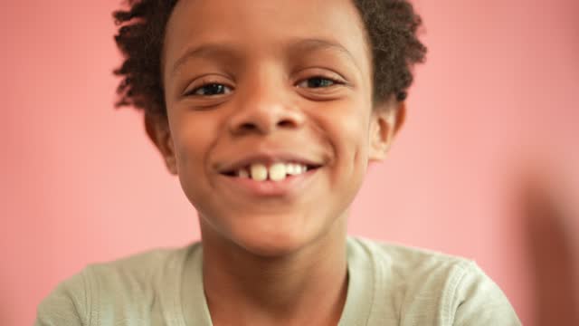 Portrait of a boy making faces on a pink background