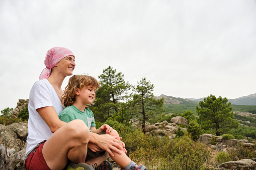 Woman with cancer enjoying nature with her son. She is wearing a pink headscarf.