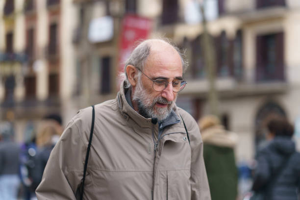 Barcelona, Spain - November 26, 2018: Senior man portrait. The main touristic street Rambla in the autumn rainy day