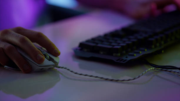 istock Cyberplayer hand using mouse in neon room closeup. Esport player resting online 1453669860