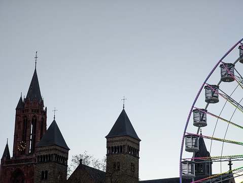 Church in the city of Maastricht and a colorful illuminated section of a Ferris wheel coming into the picture on the right