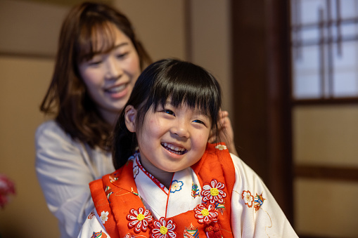 Happy little girl being dressed in kimono for Shichigosan