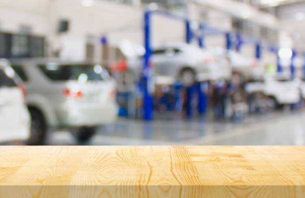 istock Empty wood table top with car service centre auto repair workshop blurred background 1453676844