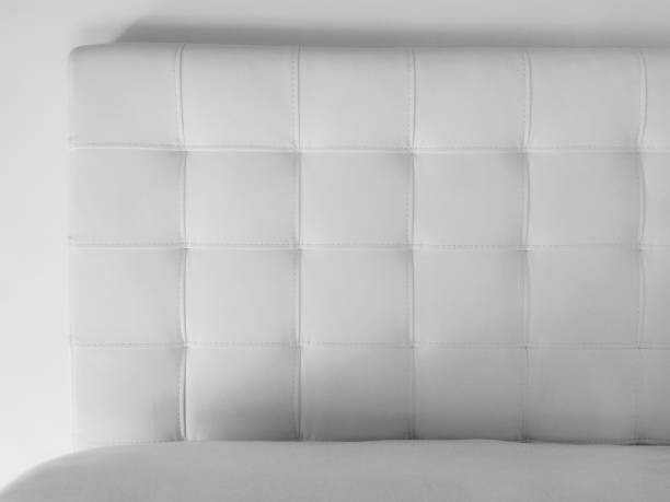 ソフトヘッドボード。本革または人工皮革とキルティング生地で作られた家具の室内装飾品。明るい壁に柔らかいヘッドボード。白黒モノクロ写真 - pillow headboard wall bedroom ストックフォトと画像